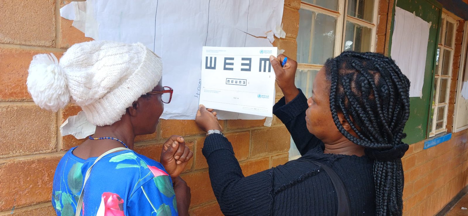 Frontline Worker dispensing reading glasses to a beneficiary during a door-to-door distribution visit in Siaya County, Kenya